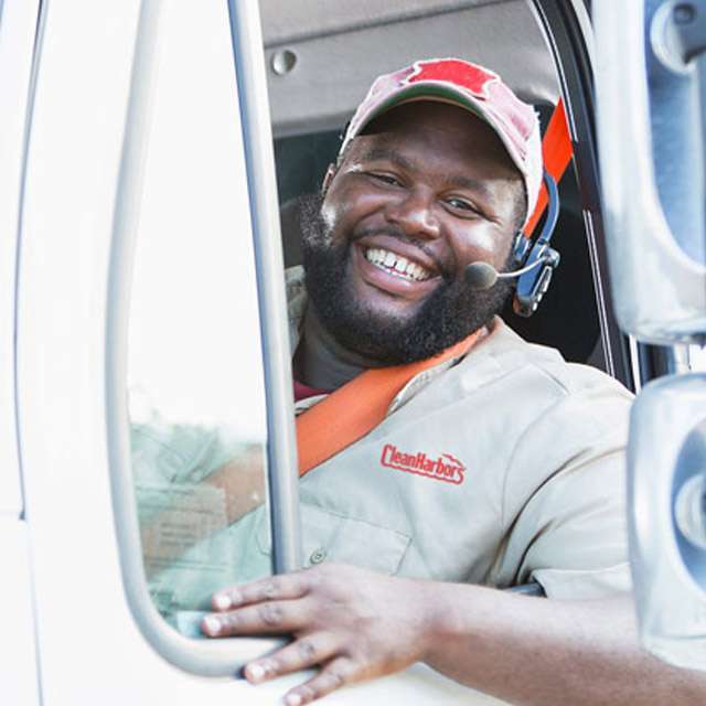 A smiling Clean Harbors driver sitting in a truck